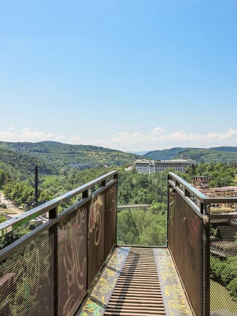 есколько зданий и памятник , Болгария платформа в виде пешеходного перехода в городе с видом на зеленые холмы, несколько зданий и памятник , Болгария